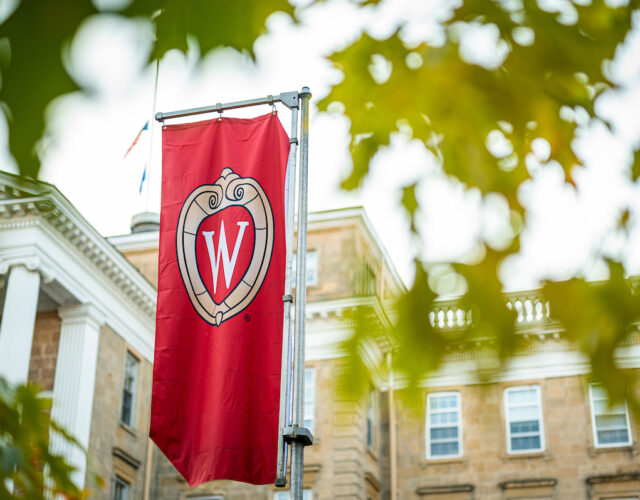 W crest banner on Bascom Hill is pictured among colors of fall leaves at University of Wisconsin-Madison.