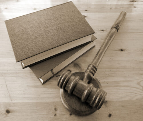 Gavel with two books on wooden table.