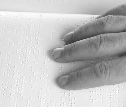 Hand reading book written in braille.