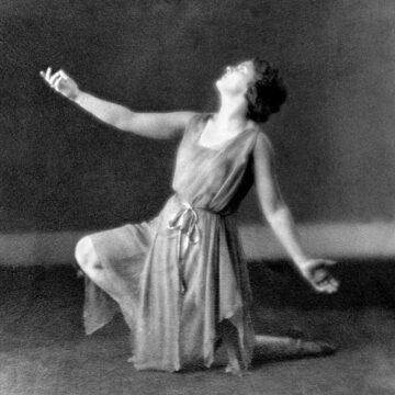 Margaret H'Doubler in dance pose kneeling on one leg with arms extended looking up.
