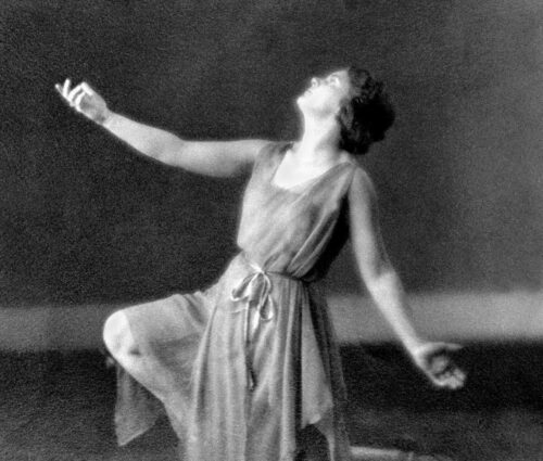 Margaret H'Doubler in dance pose kneeling on one leg with arms extended looking up.