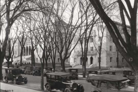 Trees and early 20th century cars lining Langdon Street with Memorial Union in background.