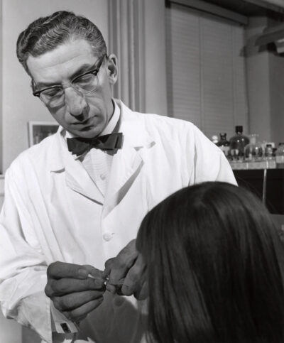 Harry Waisman applying patient's finger to glass microscope slide after finger prick.