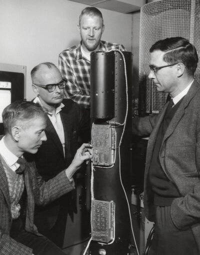 Four astronomers and academic staff examining equipment during development of Orbital Astronomical Observatory.