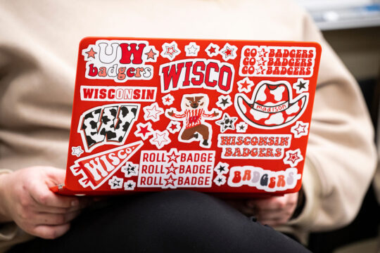 A students uses a laptop computer thoroughly decorated with Wisconsin Badgers-themed stickers.