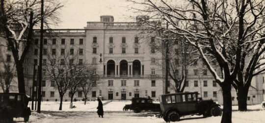 Wisconsin General Hospital on snowy day with cars out front and people walking.