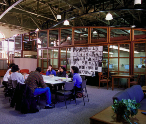 Group of students sitting around table in open room at the Armory (Red Gym).