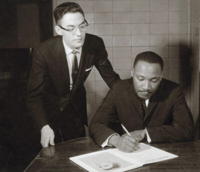 Jim Ehrman beside Martin Luther King Jr signing document.