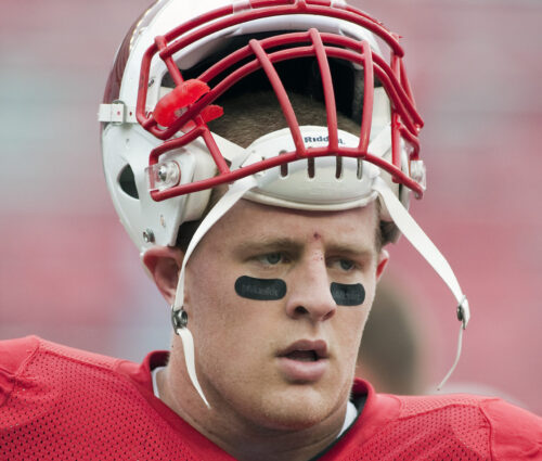 JJ Watt in Badger football uniform with unstrapped helmet on head.