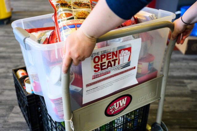 Volunteer with The Open Seat UW Student Food Pantry pushing cart containing donated groceries.