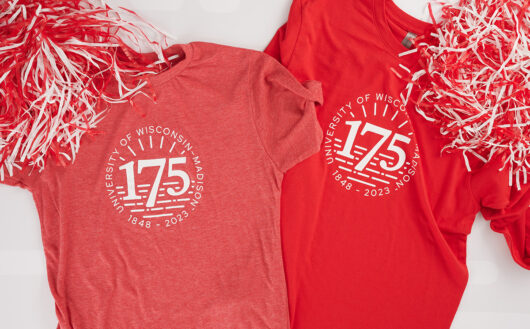 Two red 175th anniversary t-shirts laying side-by-side with red and white pom-poms in upper corners.
