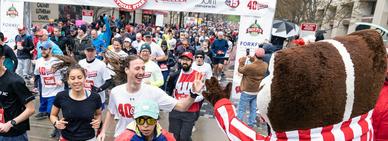 Runners at the starting line of the Crazylegs classic high-fiving Bucky Badger