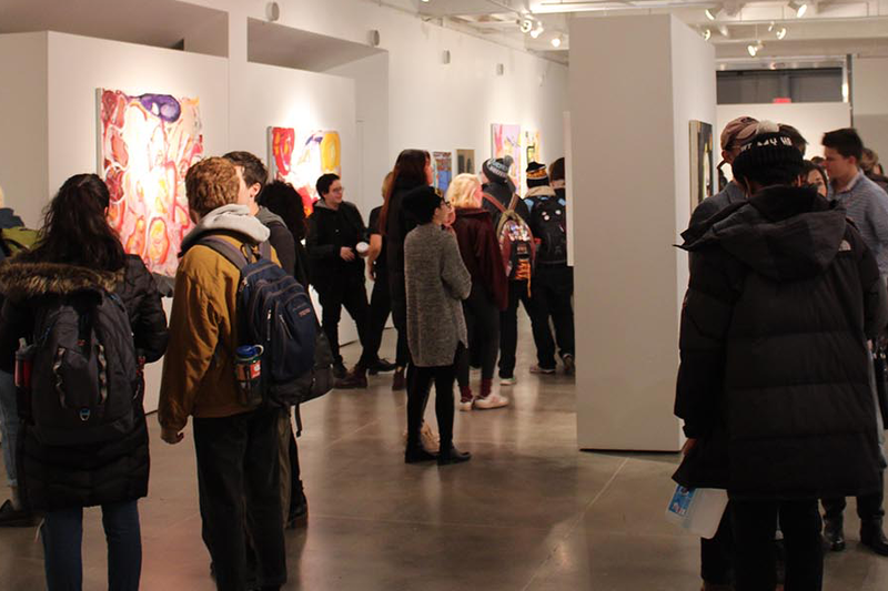 A photo of guests within a white art exhibition gallery.