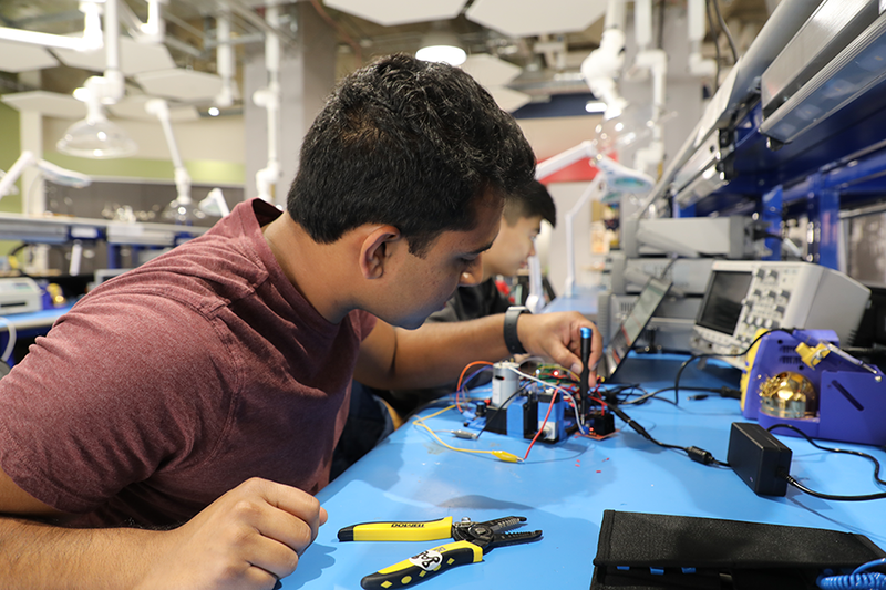 A photo of a student in Makerspace, working with cords and tools.