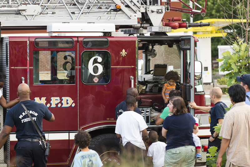 A photo of children and families interacting with a red Madison Fire Dept Engine at a previous event.