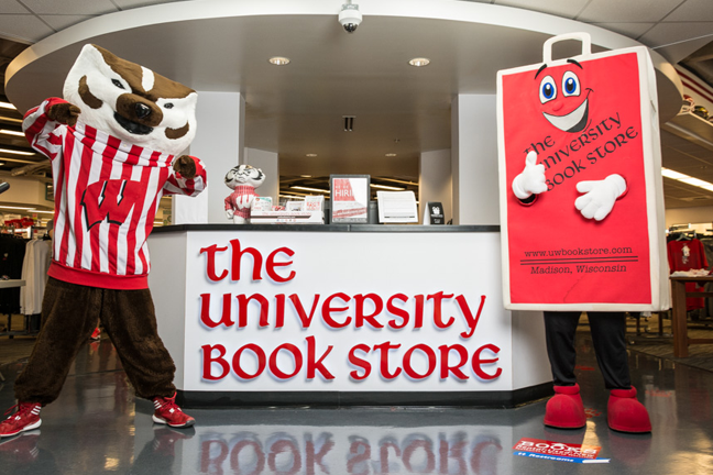 A photo of Bucky Badger and a Book Store shopping bag mascot, standing in front of the University Book Store front desk.