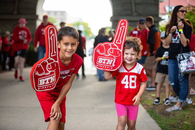 A photo of two children decked out in badger red, holding Big Ten Network foam fingers outside Camp Randall arch.
