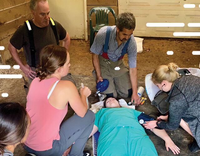 Person laying on ground getting vitals checked by a group of individuals